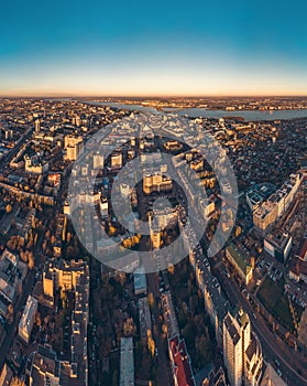 Aerial drone shot of modern city downtown with buildings from above, streets with cars in sunset