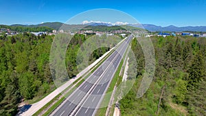 AERIAL Drone shot of motorway crossing green landscape and running toward suburb