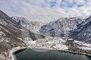 Aerial drone shot of Obertraun village in snow mountain valley by Hallstatt lake in Austria in winter