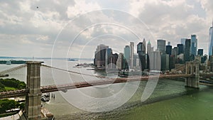 AERIAL drone shot over Brooklyn Bridge with American flag and East River view over Manhattan New York City Skyline