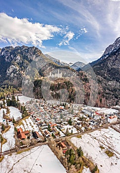 Aerial drone shot of picturesque Neuschwanstein Castle on snowy hill in winter sunlight in Germany