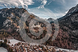 Aerial drone shot of picturesque Neuschwanstein Castle on snowy hill in winter sunlight in Germany