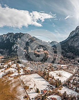 Aerial drone shot of picturesque Neuschwanstein Castle on snowy hill in winter sunlight in Germany