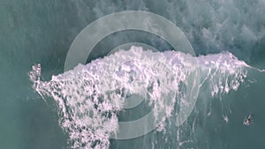 Aerial, drone shot of surfers riding the Pacific Ocean waves in Hawaii