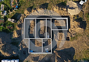 Aerial drone top down view on construction site with reinforced concrete house foundation, brick wall and materials like wall