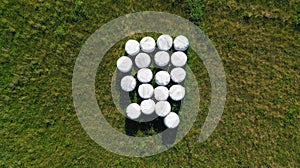 Aerial drone top down view on green meadow with foiled hay round bales stored for future use