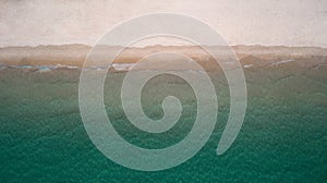 Aerial top view of sea waves crashing against the sandy beach