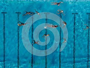 Aerial drone top view shot of people competing in water polo in turquoise water pool