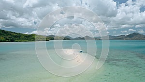 Aerial drone - tourist banca boat moored at sandbar during low tide. Surrounded islands and white clouds moving n