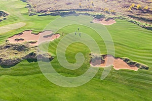 Aerial drone vibrant view of golf course in countryside, landscape field with with a rich green turf and sand bunkers summer sunny