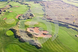 Aerial drone vibrant view of golf course in countryside, landscape field with with a rich green turf and sand bunkers summer sunny