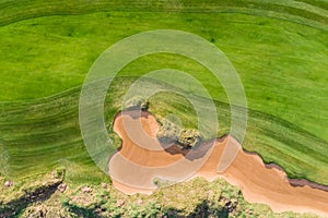 Aerial drone vibrant view of golf course in countryside, landscape field with with a rich green turf and sand bunkers summer sunny