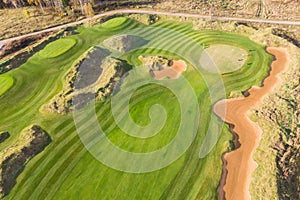 Aerial drone vibrant view of golf course in countryside, landscape field with with a rich green turf and sand bunkers summer sunny