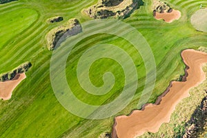 Aerial drone vibrant view of golf course in countryside, landscape field with with a rich green turf and sand bunkers summer sunny