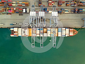 Aerial drone view above dockyard. Cargo vessel is loading containers.