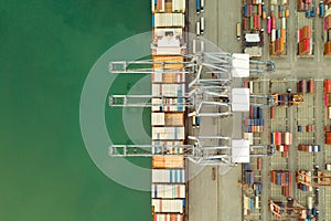 Aerial drone view above dockyard. Cargo vessel is loading containers.