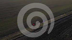 Aerial drone view from above of family ride on bikes outdoors on the spring field