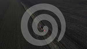 Aerial drone view from above of family ride on bikes outdoors on the spring field