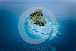 Aerial drone view of a beautiful secluded cliff island surrounded by azure turquoise blue ocean water. Bacuit