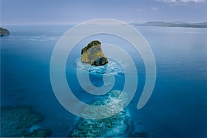 Aerial drone view of a beautiful secluded surreal cliff island surrounded by azure turquoise blue ocean water. Bacuit