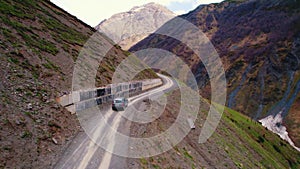 Aerial drone view of black off-road car on dangerous dirt road between in the mountain hills. SUV.