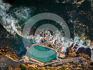 Aerial drone view of Bronte Ocean Pool in Sydney during sunrise in soft early morning light, New South Wales Australia