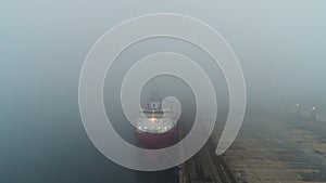 Aerial drone view of cargo ship and cranes in fog in the sea harbor