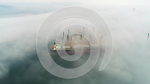 Aerial drone view of cargo ship and industrial cranes in fog in the sea harbor Varna, Bulgaria