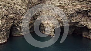 Aerial drone view of caves under a Slave cliff or Traelanipan, Faroe Islands.