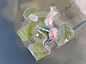 Aerial drone view children playground in the form of a puzzle piece. Colorfull recreation area with slide, swing and