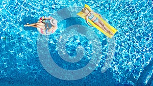 Aerial drone view of children in swimming pool from above, happy kids swim on inflatable ring donuts, girls have fun in water