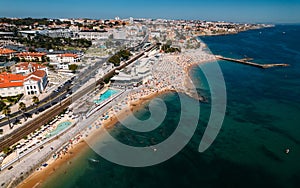 Aerial drone view of crowded Tamariz beach in Estoril, Portugal during the summer