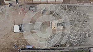 Aerial drone view of a demolition site. Excavator loading concrete and steel rubble onto the truck