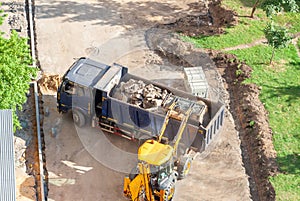 Aerial drone view excavator loading the tipper truck at the construction site. Construction equipment concept.