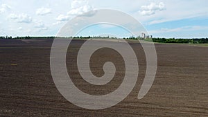 Aerial drone view flight over huge plowed field and blue sky. Skyline, horizon.