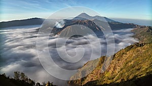 Aerial drone view fly pass hill to reveal Bromo volcano in a background, Java, Indonesia