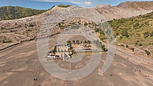 Aerial drone view fly pullback and tilt up to reveal Bromo volcano crater, Indonesia