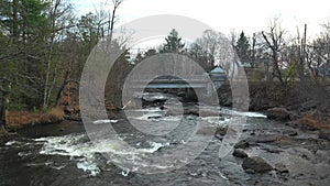 Aerial drone view, flying at low angle over the rapids of the river in Brownsburgh-Chatham and moving towards the small bridge