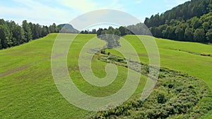 Aerial drone view flying mid-air above a bright green field