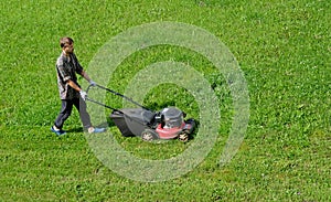 Aerial drone view of gardener mowing overgrown lawn with motorized lawnmower in the garden. Landscaping service, gardening