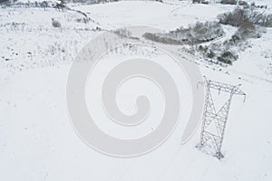 Aerial drone view of a high voltage power line tower in a snowy landscape. Galicia, Spain