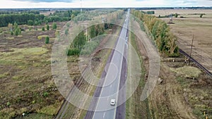 Aerial drone view of highway. A convoy of cars moving along a two-lane highway.