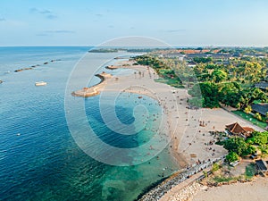 Aerial drone view of Holiday In Sanur Beach, Bali, Indonesia with ocean, boats, beach, villas, and people