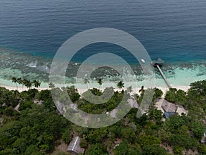 Aerial Drone view of a house reef and a wood dock on a paradise beach in Raja Ampat, Indonesia