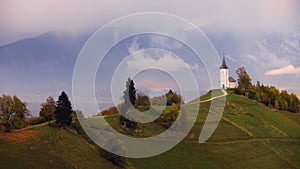 Aerial drone view of Jamnik, Slovenia. Rainbow, Alps and Church of St. Primoz