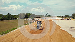 Aerial drone view of a landscape with a sand dozer working on a construction site of a new expressway.