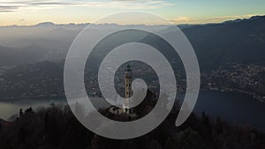 Aerial drone view of a lighthouse over Lake Como skyline with sunset light