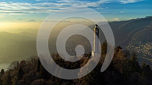 Aerial drone view of a lighthouse over Lake Como skyline with sunset light