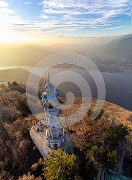 Aerial drone view of a lighthouse over Lake Como skyline with sunset light