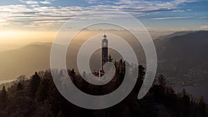 Aerial drone view of a lighthouse over Lake Como skyline with sunset light